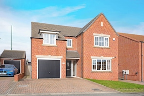 A two-story brick house with a garage, a front door, and a small window.