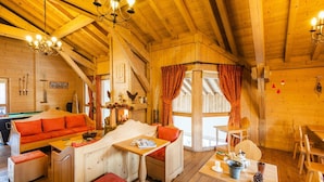 Uma cabana de madeira acolhedora, com mesa de bilhar, lareira e sala de jantar.