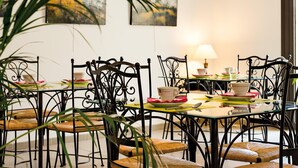 A dining area with metal chairs and tables, a lamp, and artwork on the wall.