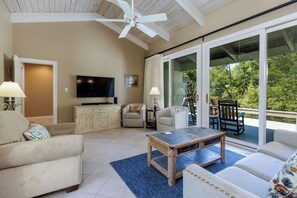 Ein Wohnzimmer mit Deckenventilator, Flachbildfernseher, Couchtisch und Sofa.