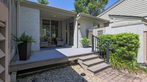Une maison dotée d’un porche abrité, d’un espace salon extérieur et d’un escalier menant à l’entrée.