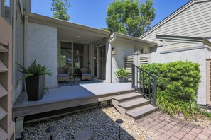 A house with a covered porch, outdoor seating, and a staircase leading to the entrance.