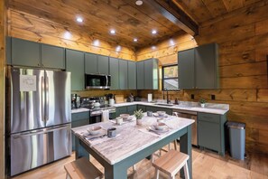 A modern kitchen with wooden walls, stainless steel appliances, and a marble countertop. - Smoky Sunset Getaway -Brand New Beautiful Mountain Cabin (Sevierville)