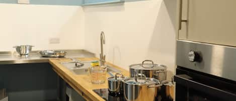 Une cuisine moderne dotée d’appareils électroménagers en acier inoxydable, d’un plan de travail en bois et d’un four encastré.