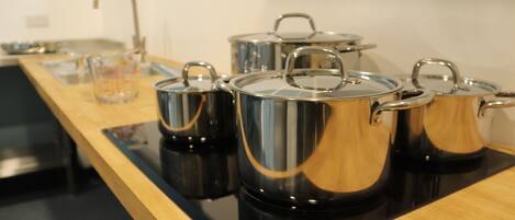 A kitchen with stainless steel pots on a black induction cooktop.