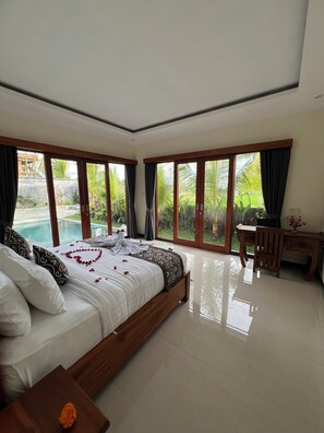 Ein Schlafzimmer mit Bett, Schreibtisch und Blick auf einen Swimmingpool.
