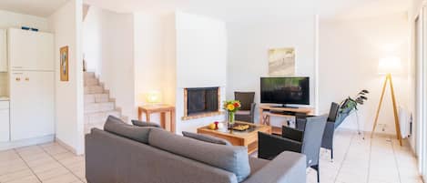 A modern living room with a sofa, TV, and a dining area.