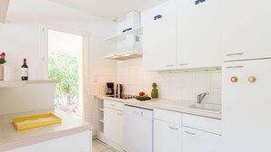A modern kitchen with white cabinets, a coffee maker, and a pineapple on the counter. - Superior Villa Escape in Lacanau (Lacanau)
