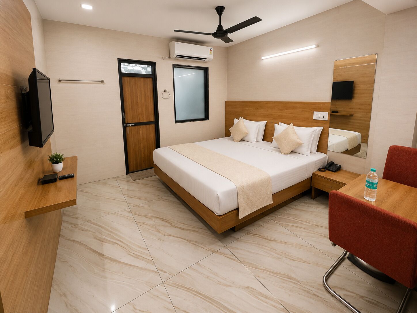 A hotel room with a bed, bedside table, chair, TV, and a ceiling fan.