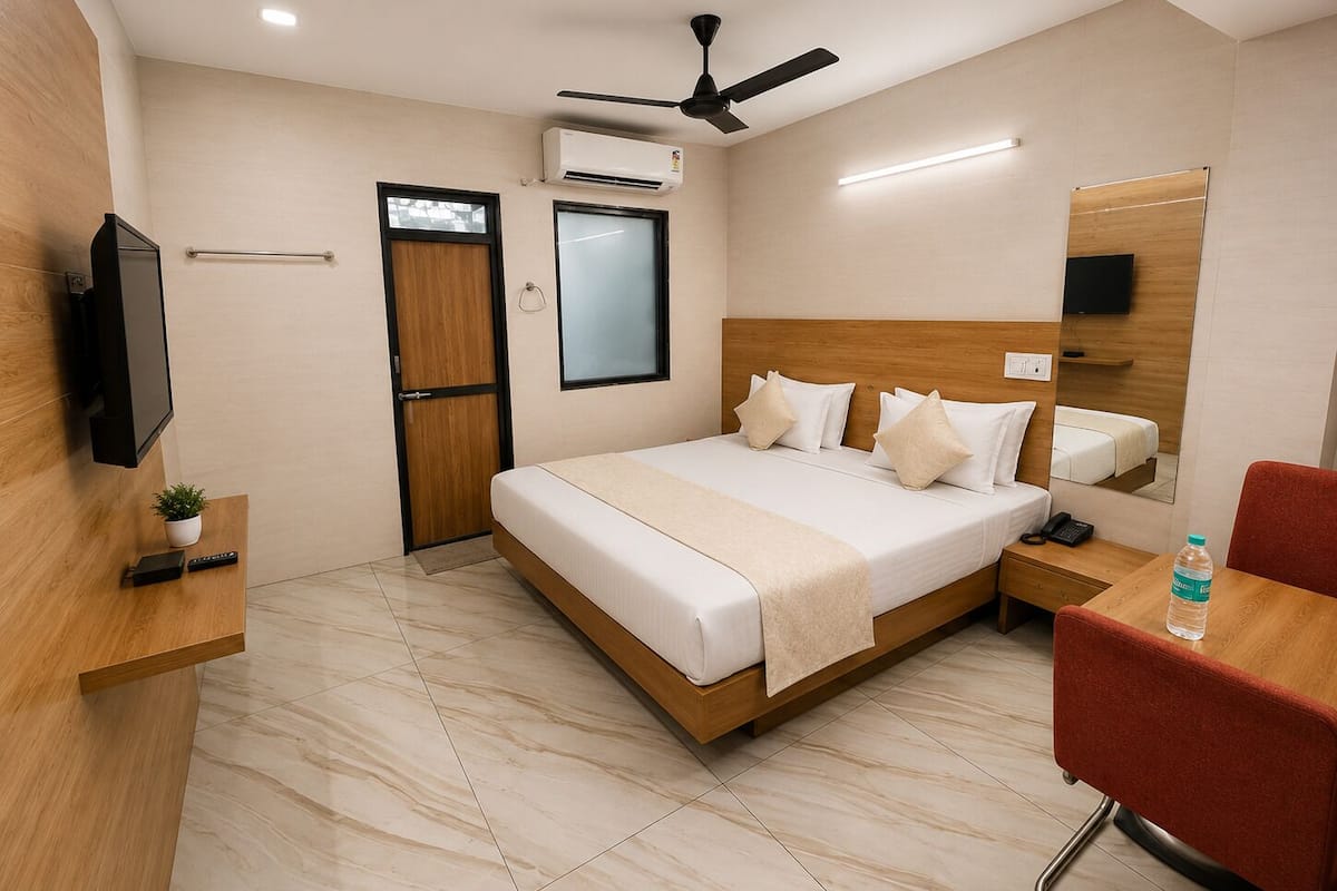 Una habitación de hotel con cama, mesita de noche, silla, televisor y ventilador de techo.