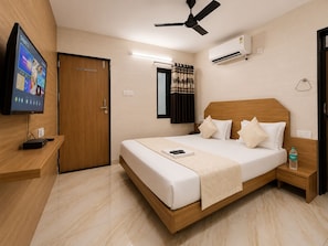 A hotel room with a bed, a TV, a ceiling fan, an air conditioner, and a window with curtains. - Hotel RR (Rajkot)