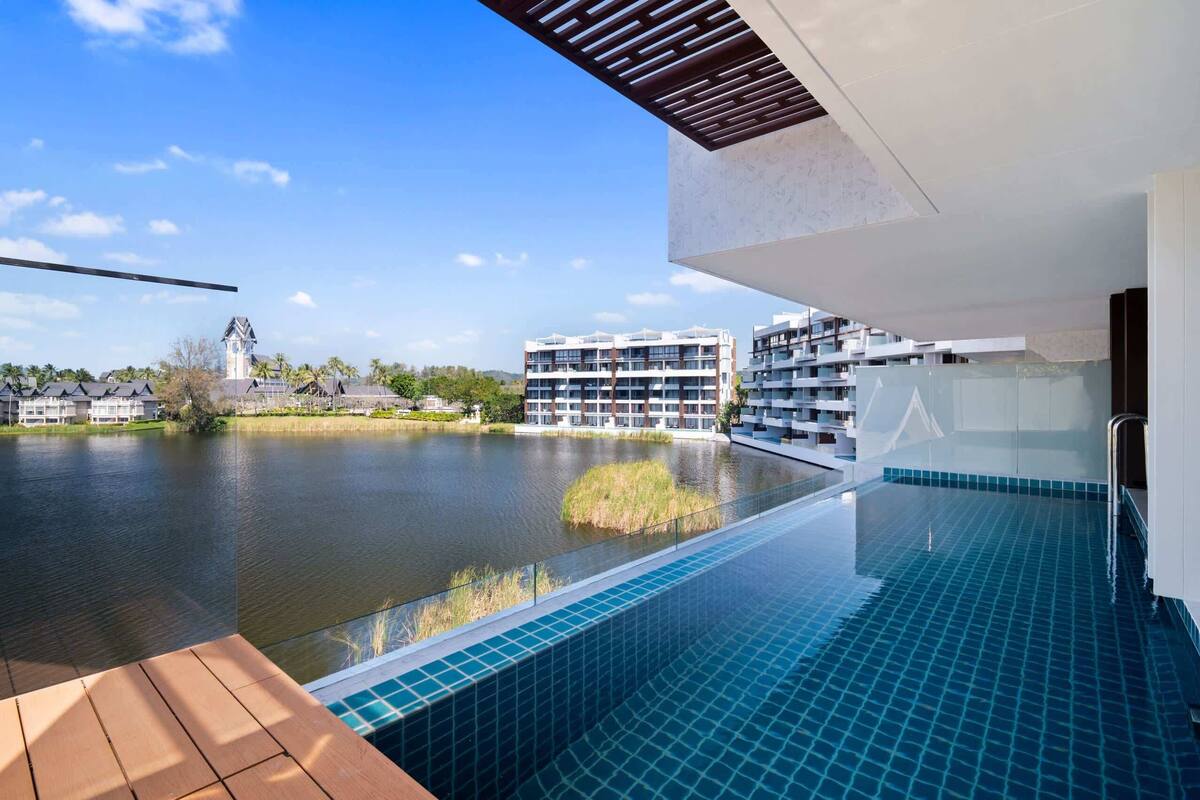 A modern hotel with a pool overlooking a lake, featuring a clear view of the surrounding buildings and a traditional tower.