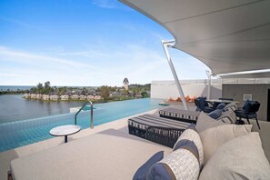 A poolside area with lounge chairs and a view of a body of water and buildings in the distance. - Angsana Oceanview Residences Building 2 in Laguna by Banyan Living (Choeng Thale)