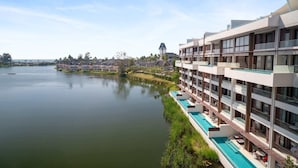 A hotel with a pool, multiple balconies, and a view of a calm lake. - Angsana Oceanview Residences Building 2 in Laguna by Banyan Living (Choeng Thale)