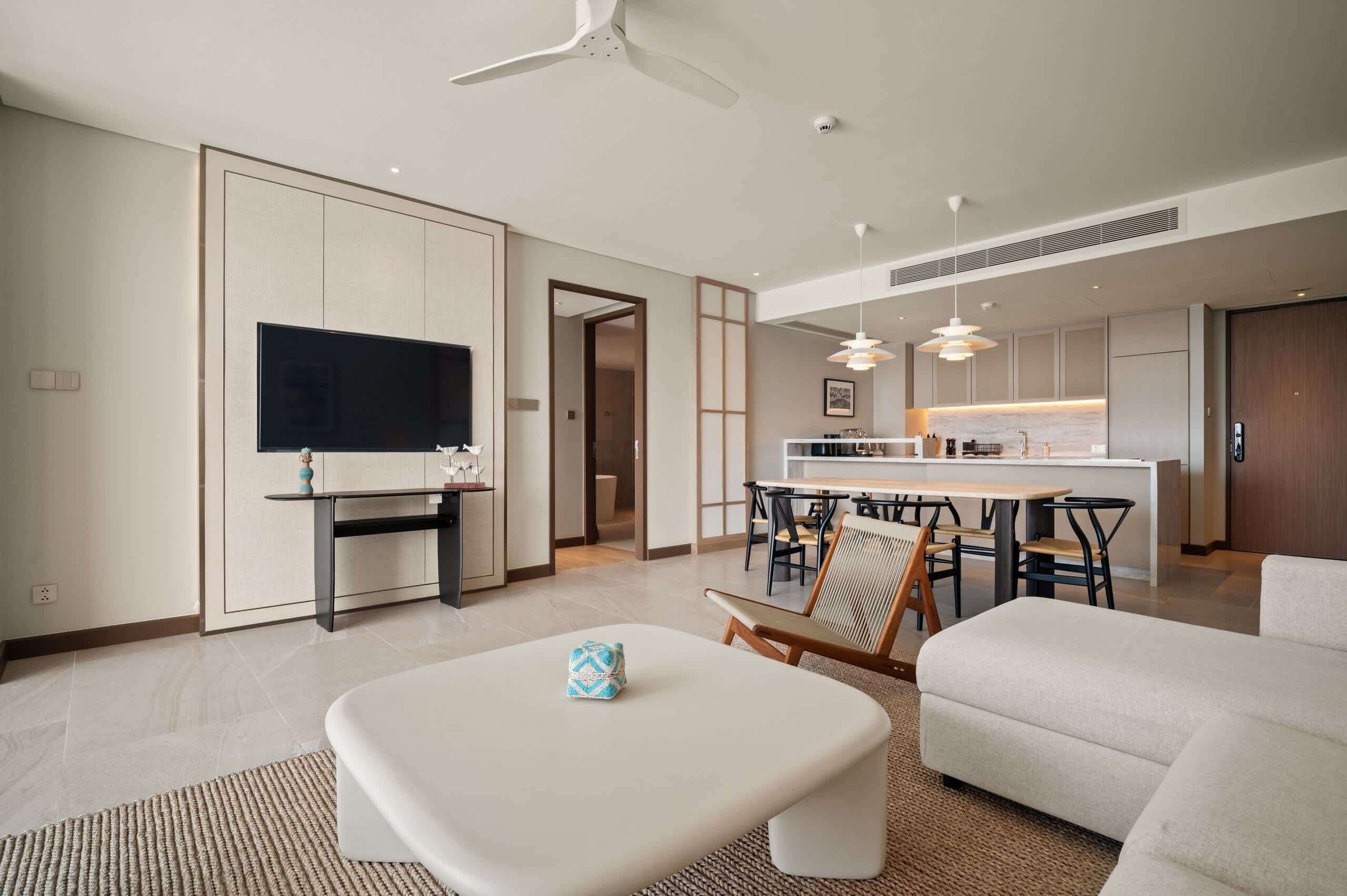 Un soggiorno moderno con una televisione a schermo piatto, un'area pranzo con una cucina sullo sfondo e una ventola a soffitto.
