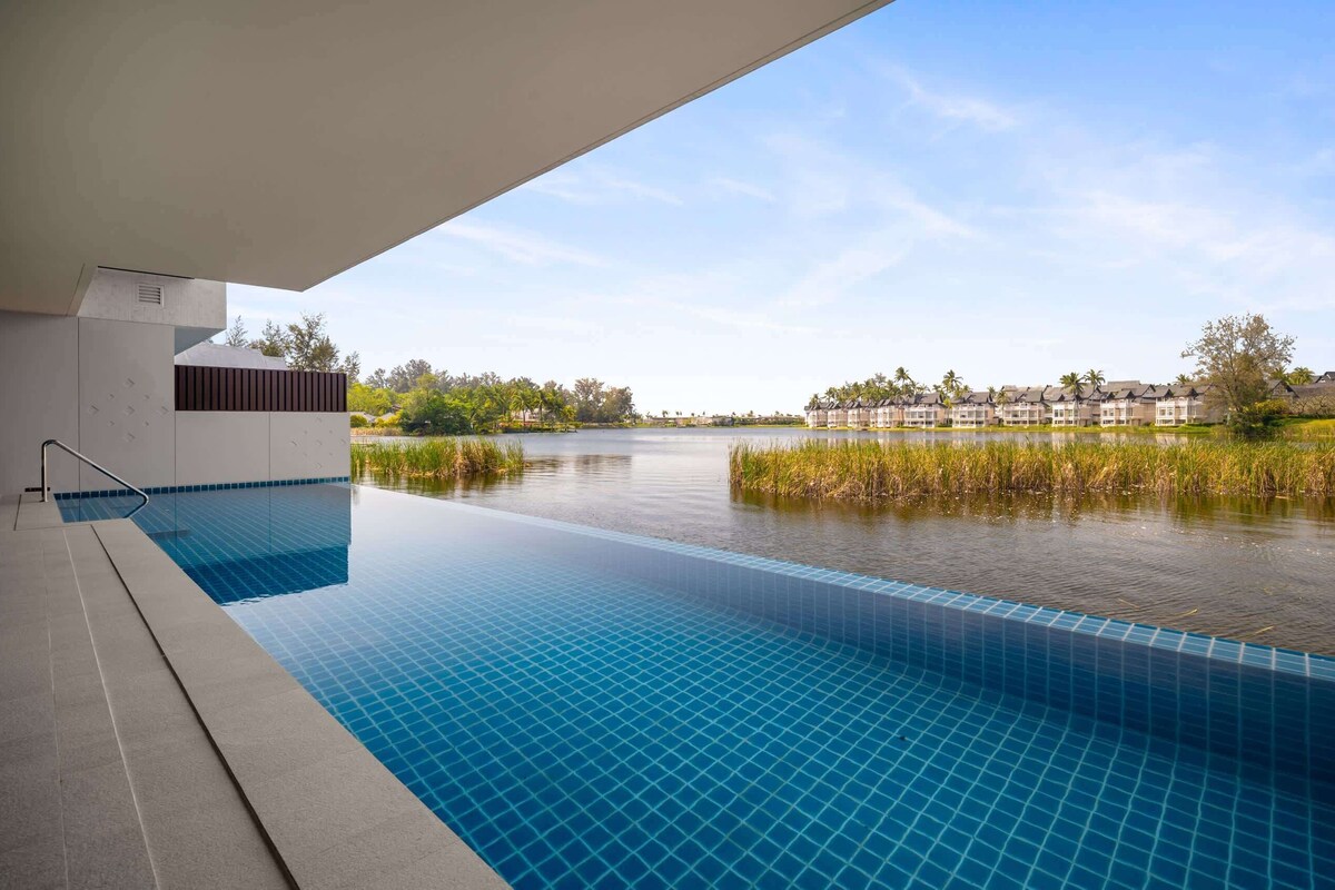 An infinity pool with a clear view of a lake and buildings in the background.