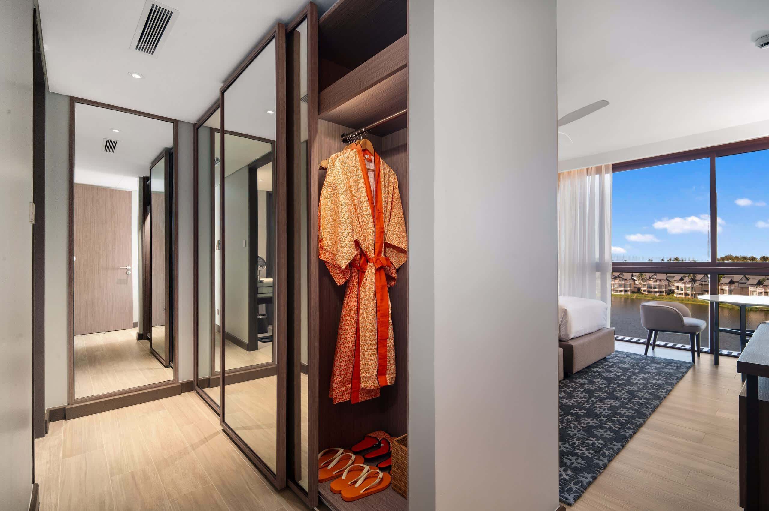 Une chambre d’hôtel dotée d’un placard avec porte coulissante, d’un lit, d’une table à manger et offrant une vue sur une étendue d’eau.