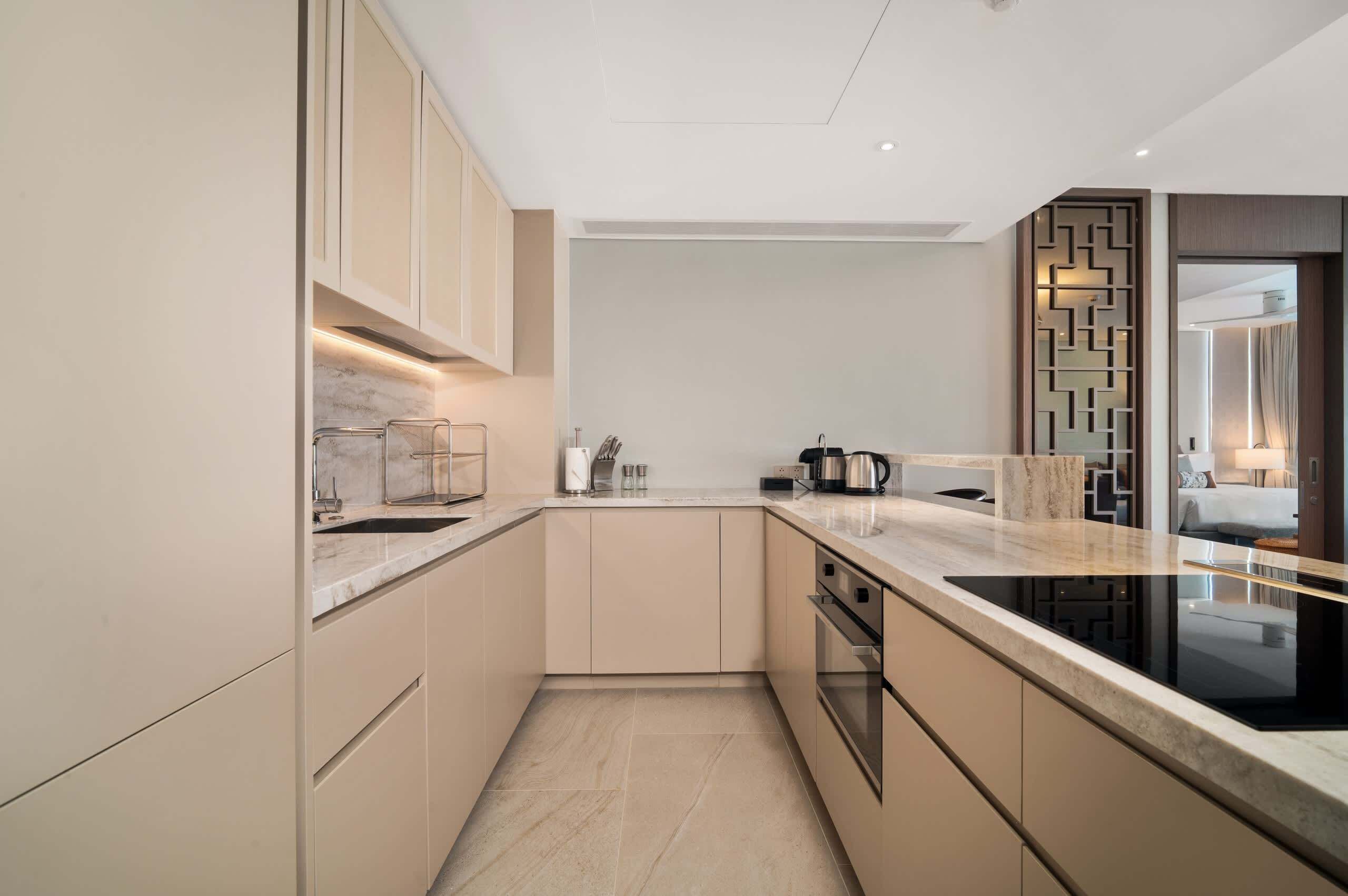 A modern kitchen with a marble countertop, built-in oven, and a decorative wall panel.
