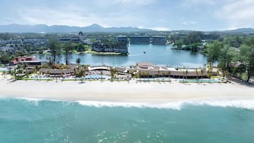 A resort with beachfront accommodations, a pool area, and a view of the surrounding landscape.
