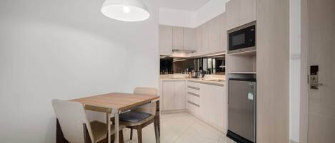 Una cocina moderna con una mesa de comedor, sillas, un refrigerador y un microondas.