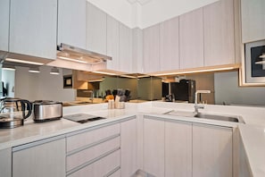 A modern kitchen with a central island, built-in appliances, and ample counter space. - Cassia Residences Building 2 in Laguna by Banyan Living (Choeng Thale)