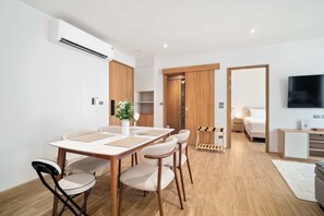 A modern room with a dining table, chairs, a TV, a bed, and a wardrobe. - Laguna Beach Residences Seashore by Banyan Living (Choeng Thale)