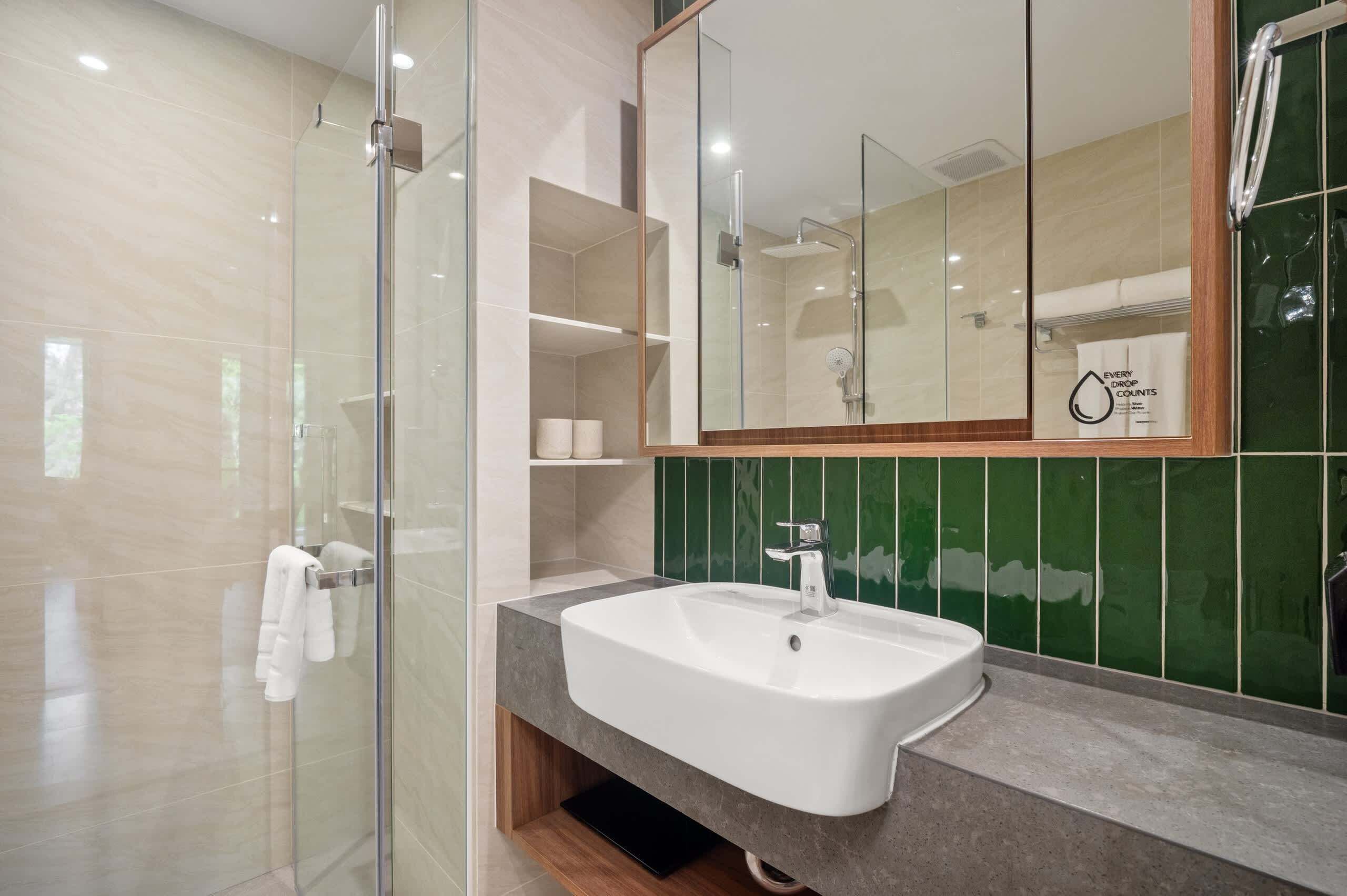 A modern bathroom with a glass shower enclosure, a white sink, and a large mirror.