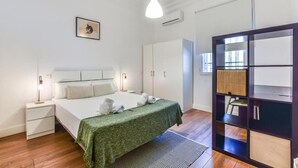 A bedroom with a bed, bedside tables, a wardrobe, a hanging light fixture, and a built-in bookshelf. - Retiro VII (Madrid)