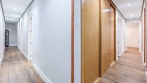 A hallway with wooden flooring, white walls, and wooden doors. - Retiro VII (Madrid)