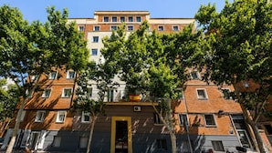 A multi-story building with a central entrance, trees in front, and bicycles parked outside. - Retiro VII (Madrid)