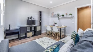 A modern living room with a sofa, a dining table with chairs, a TV, and a bookshelf. - Retiro VII (Madrid)