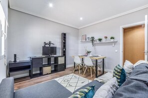 Ein modernes Wohnzimmer mit einer Couch, einem Esstisch mit Stühlen, einem Fernseher und einem Bücherregal.