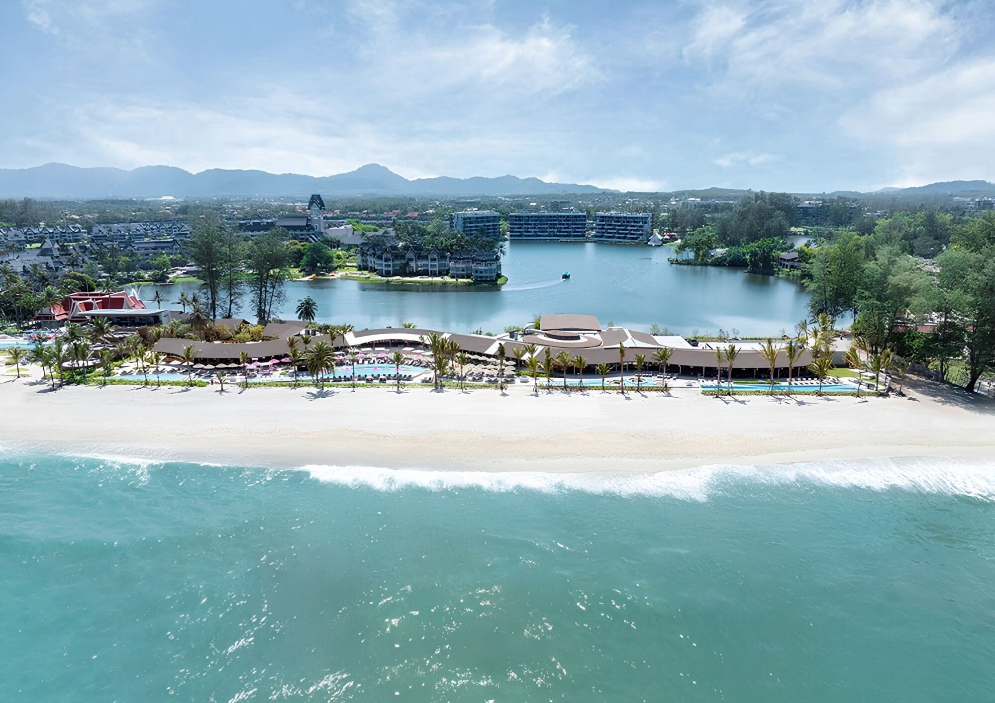 A resort with beachfront accommodations, a pool area, and a view of the surrounding landscape.