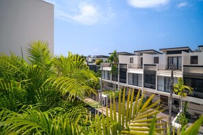 A modern multi-story residential building with balconies, surrounded by lush greenery. - Laguna Parkside Residences by Banyan Living (Choeng Thale)
