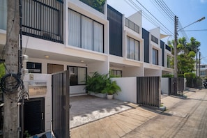 A modern multi-story residential building with balconies, large windows, and a gated entrance. - Laguna Parkside Residences by Banyan Living (Choeng Thale)