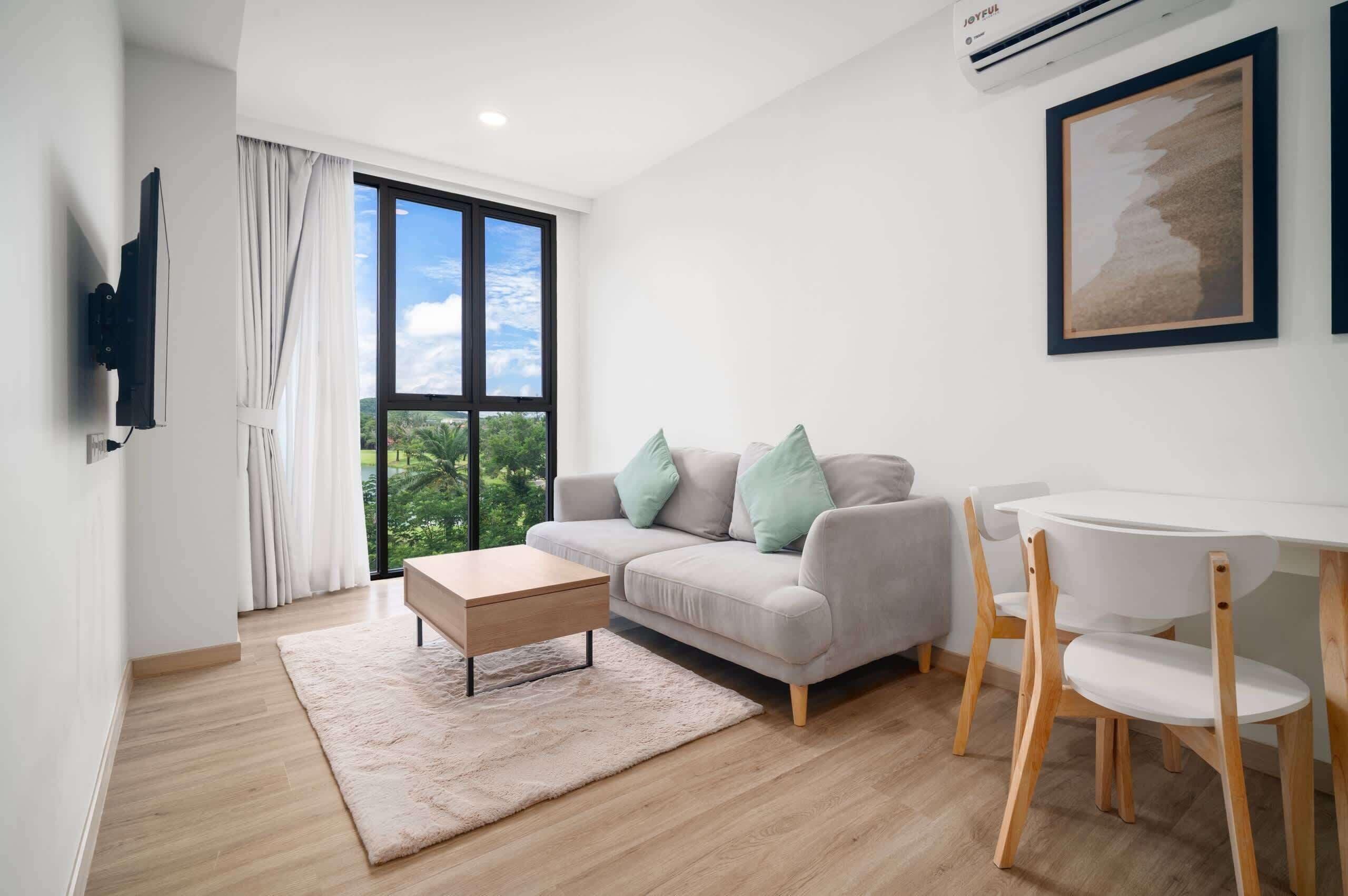 A modern living room with a sofa, a coffee table, a TV, and a dining table with chairs.