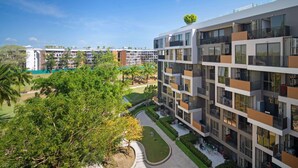 A multi-story building with balconies, a rooftop garden, and a courtyard with trees and seating areas. - Skypark Aurora in Laguna by Banyan Living (Choeng Thale)