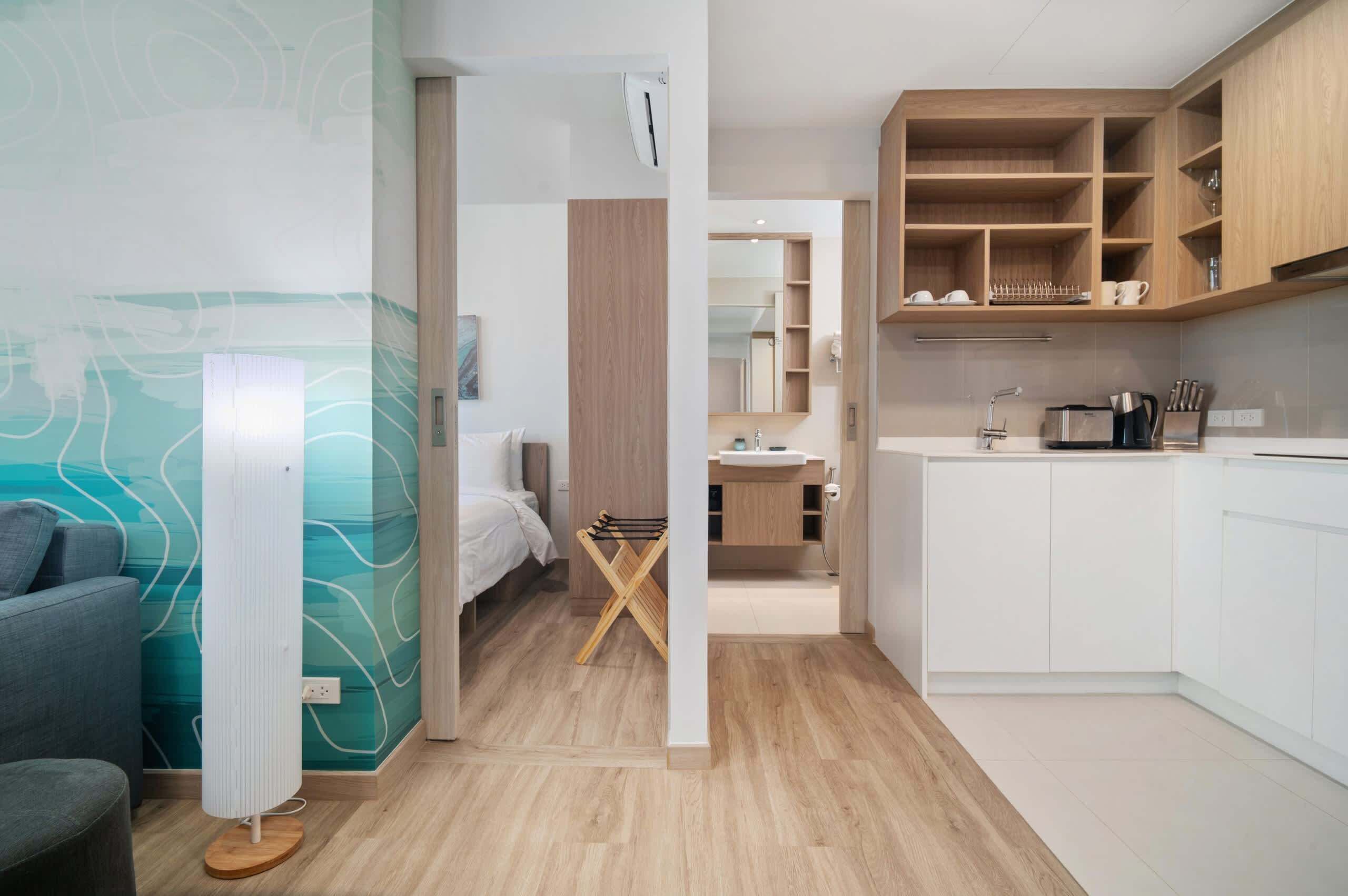 Een moderne kamer met een bed, bureau en kitchenette.