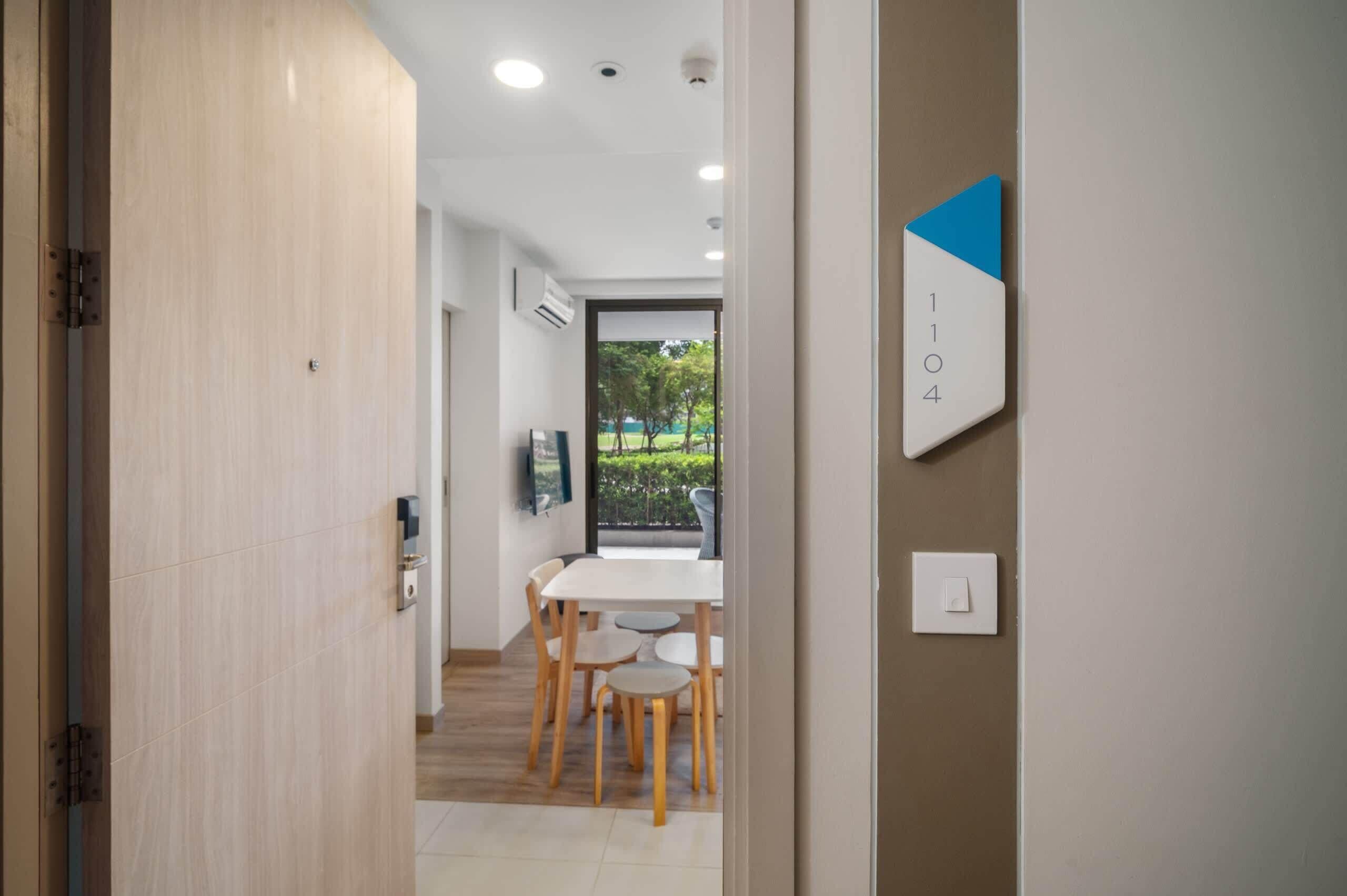 A modern interior with a dining area, a view through a glass door, and a wall-mounted number sign.