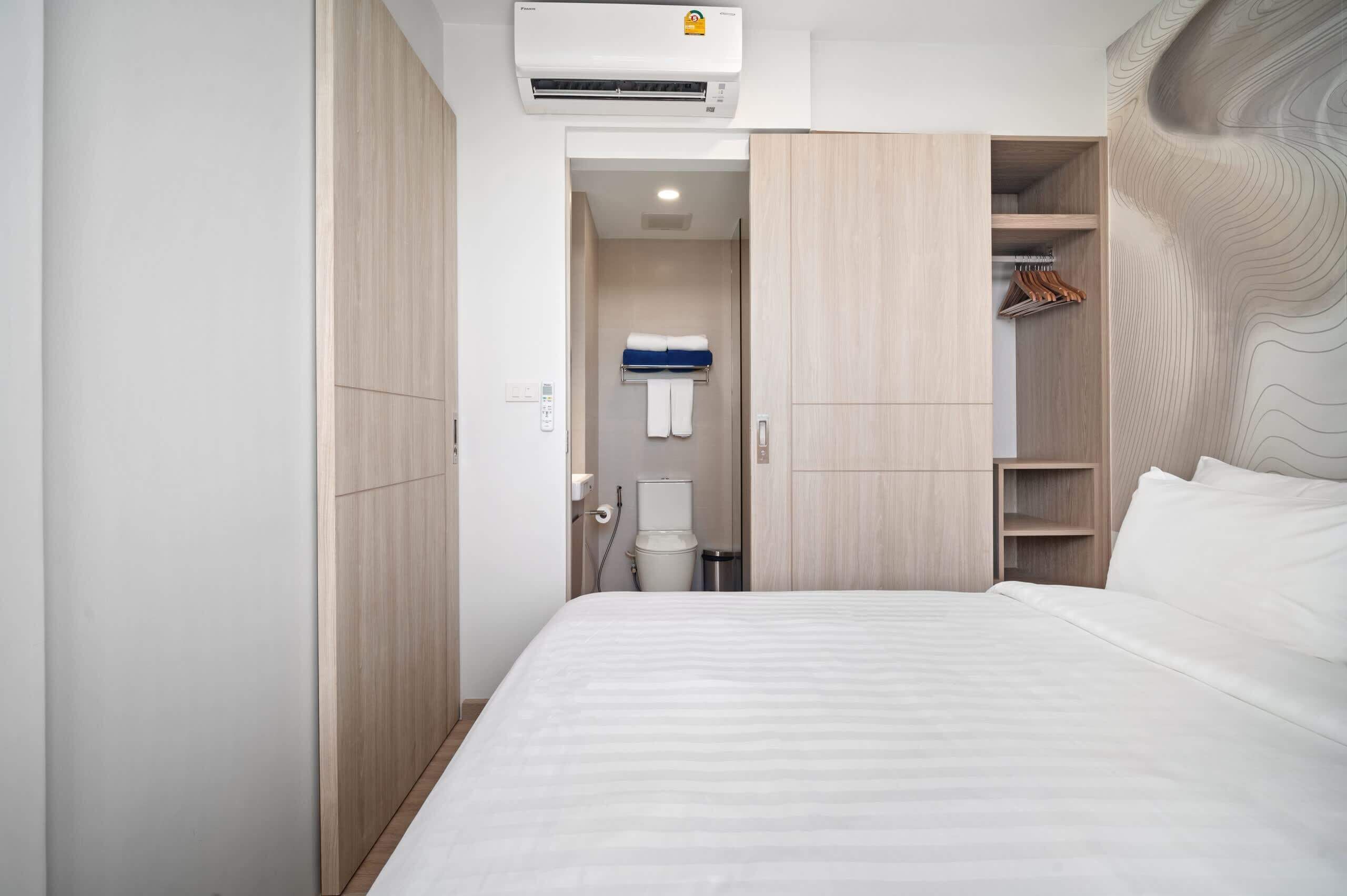 Ein Hotelzimmer mit Bett, Schrank und einem Badezimmer mit Toilette und Handtuchhalter.