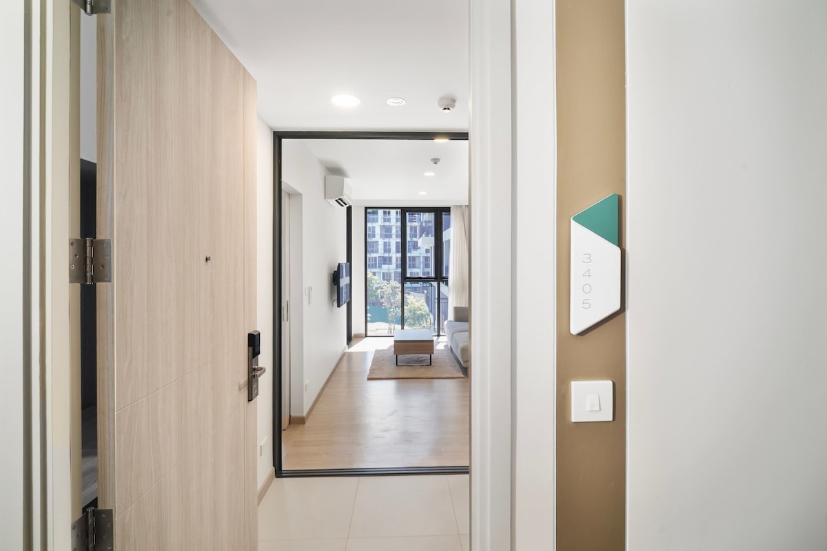 A hallway with a wooden door, a light switch, and a number sign on the wall.