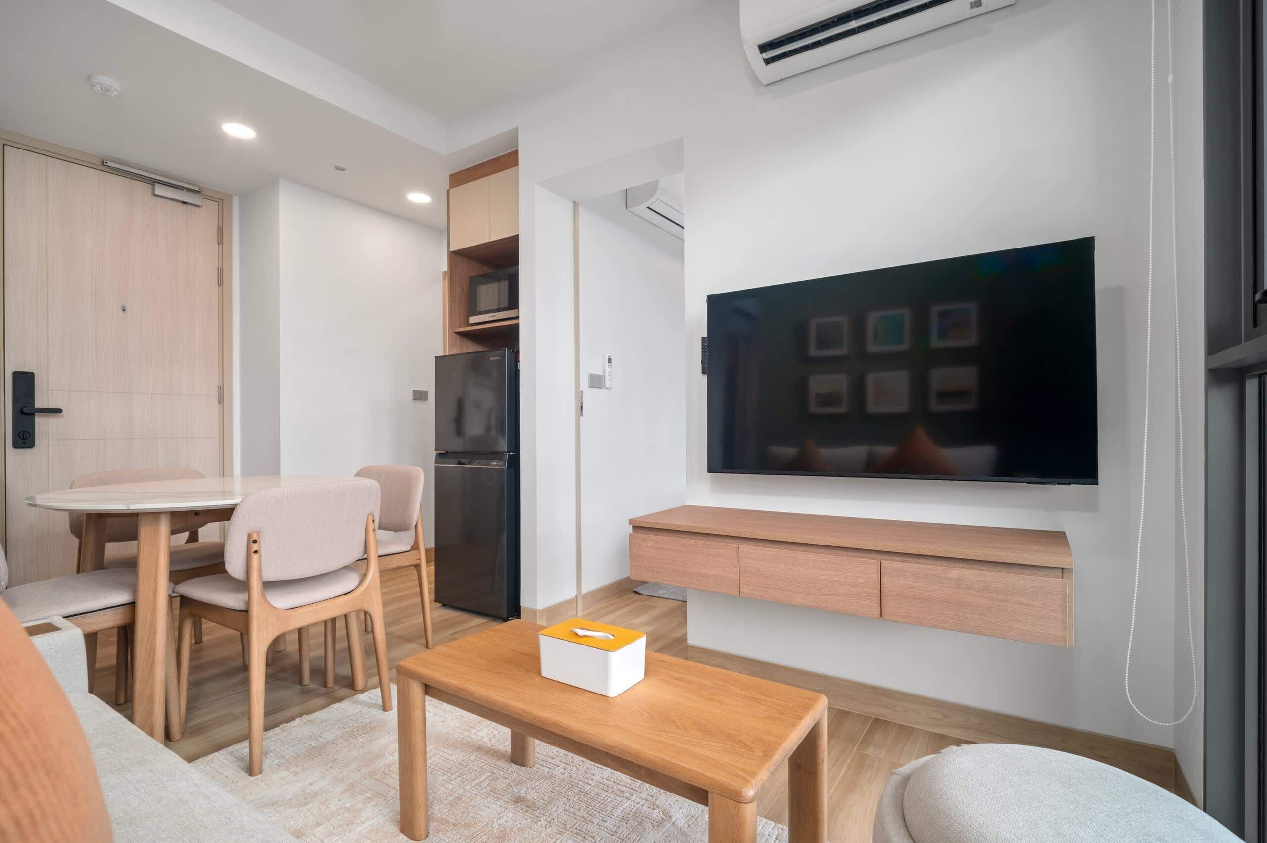 Una sala de estar moderna con un televisor de pantalla plana, muebles de madera, un comedor y almacenamiento empotrado.