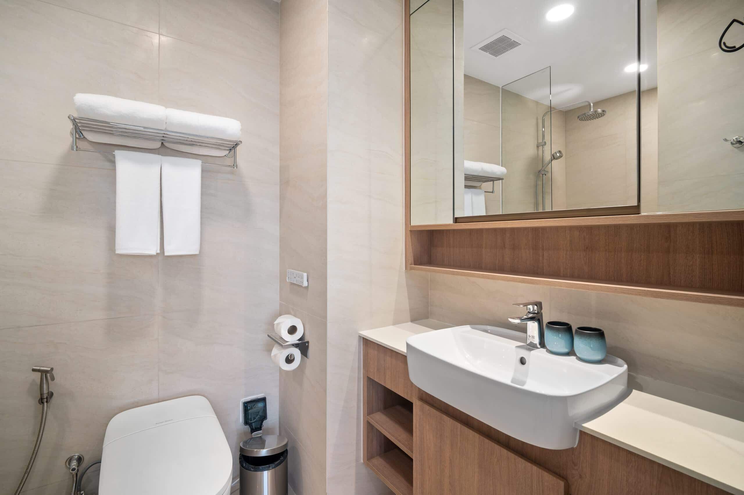 Une salle de bain moderne équipée d’un WC, d’un lavabo, d’un miroir et d’un porte-serviettes.