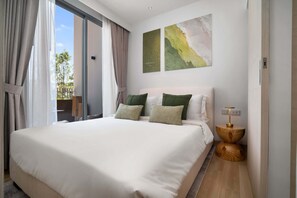 A modern hotel room with a large bed, a view through a sliding door, and two abstract wall art pieces. - Skypark Celeste Building 5 in Laguna by Banyan Living (Choeng Thale)