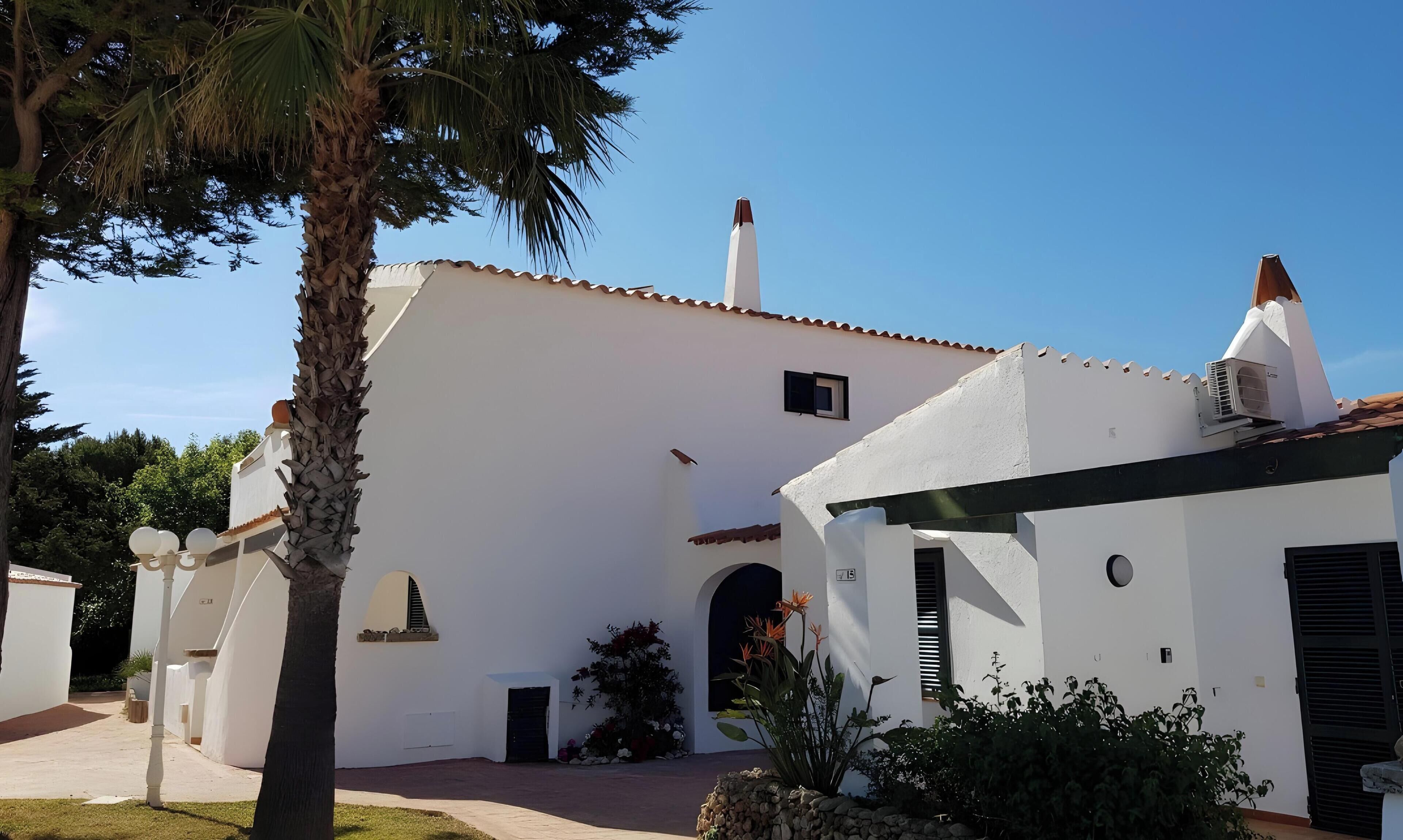 Un edificio blanco con techo de tejas, una ventana pequeña y una puerta.