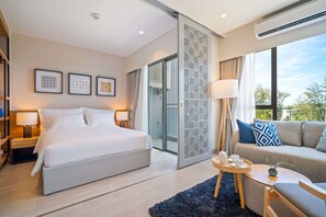 Ein modernes Hotelzimmer mit einem großen Bett, einem Schlafsofa, einem kleinen Tisch und einer Schiebetür zum Balkon.
