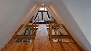 A loft bedroom with a wooden floor, a bunk bed, and a skylight. - Maison des Vergers, nature meets craftsmanship (Hoffen)