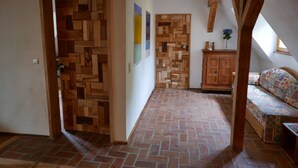 A room with a brick floor, wooden walls, a sofa, and a cabinet. - Maison des Vergers, nature meets craftsmanship (Hoffen)