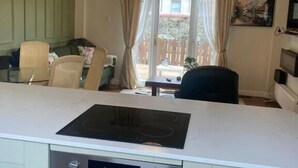 A kitchen with a built-in stove, oven, and a dining area with a table and chairs. - Bunker Golf Cottage (Prestwick)