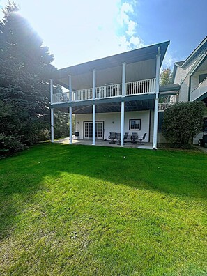 A two-story house with a covered porch, a lawn, and a garage. - The Chief's Landing- Lower Level Condo (Bellaire)